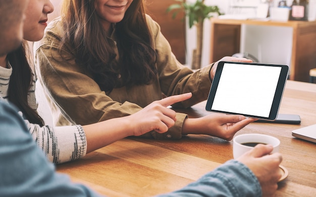 Pessoas usando e olhando para o mesmo modelo tablet pc juntos na mesa de madeira