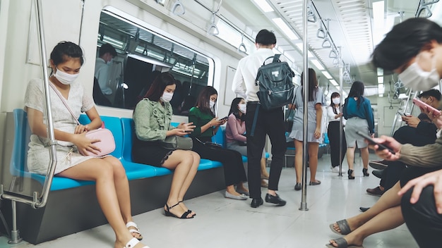 Pessoas usando máscaras em um trem público de metrô lotado