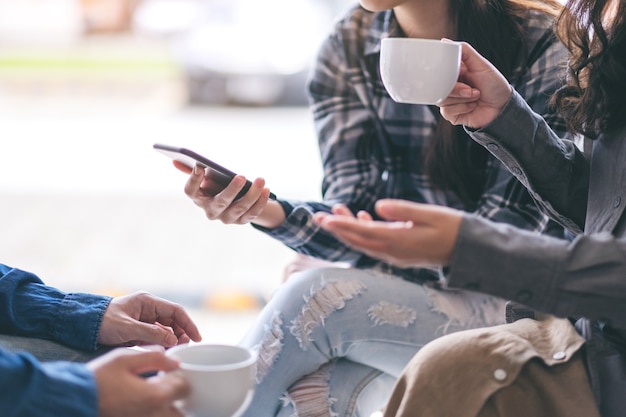 Pessoas usando telefone, conversando e tomando café juntas