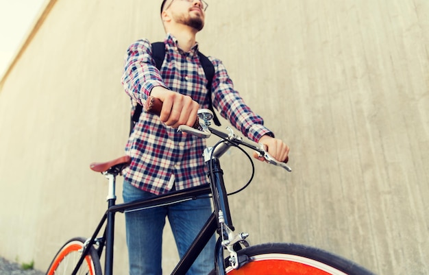 pessoas, viagens, turismo, lazer e estilo de vida - close-up do homem jovem hipster com bicicleta de marcha fixa e mochila na rua da cidade