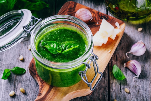 Pesto casero en un tarro de cristal sobre un fondo rústico de madera