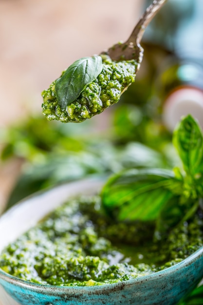 Pesto de hojas de albahaca fresca sobre mesa de madera.