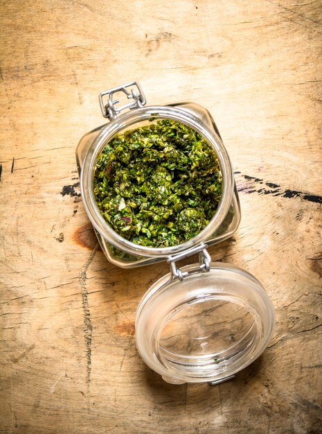 Pesto in einem Glas. Auf einem Holztisch.