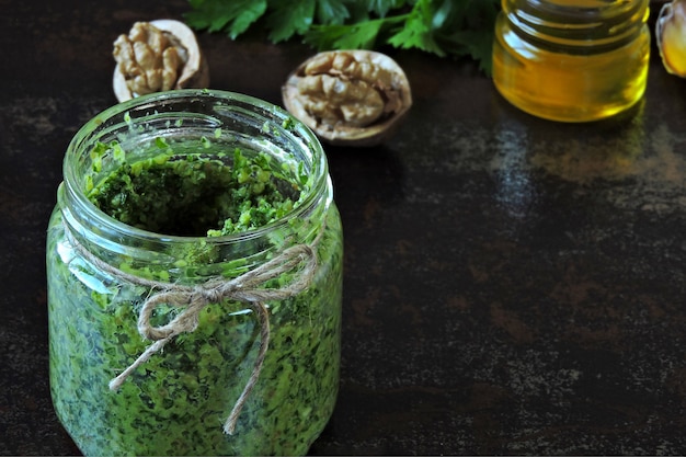 Pesto de nuez con perejil. Salsa de pesto casera en un frasco. Vista superior. Pesto vegano con nuez y perejil.