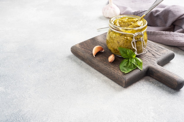 Pesto-Sauce im Glas, frische Basilikumblätter und Knoblauch. Platz kopieren