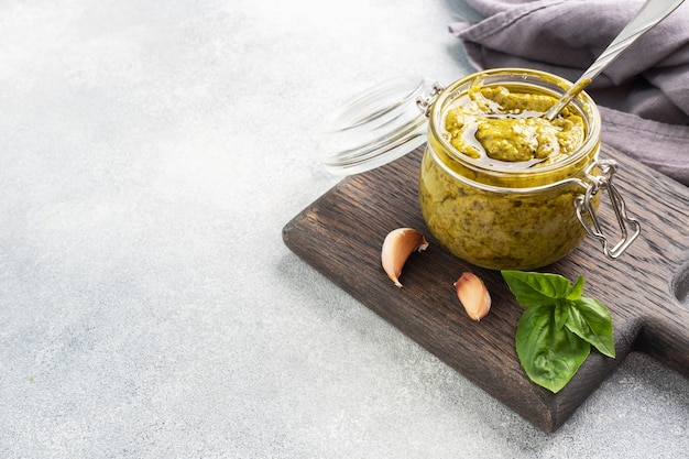 Pesto-Sauce in einem Glas frische Basilikumblätter und Knoblauchkopienraum