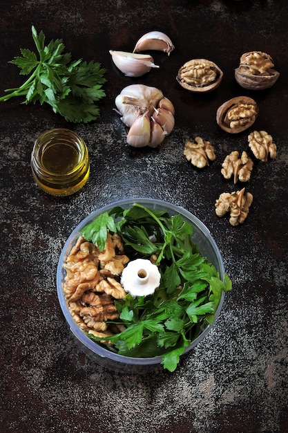 Pesto-Sauce mit Petersilie und Walnüssen kochen. Walnuss Pesto Rezept. Zutaten für Pesto in einem Mixbecher. Draufsicht.