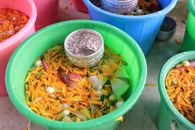 Pétalo de caléndula y jazmín en un pequeño cubo de plástico con tazón de plata Festival Songkran en Tailandia