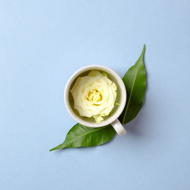 Pétalo de rosa en una taza de té con hojas verdes