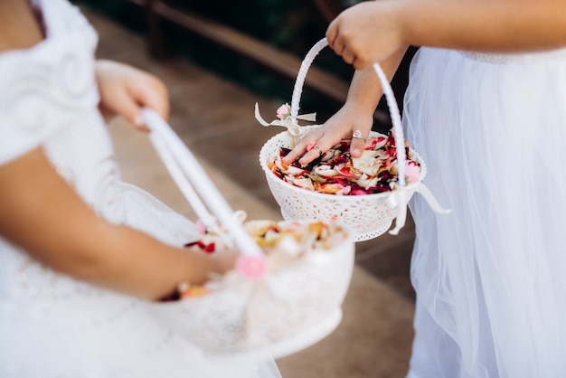 Pétalos de rosa para la ceremonia en cestas nupciales en manos de los niños