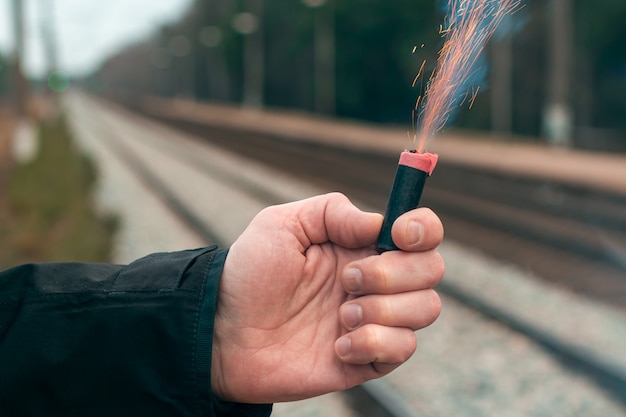 El petardo en una mano. Hombre que sostiene una petarda ardiente en su mano.