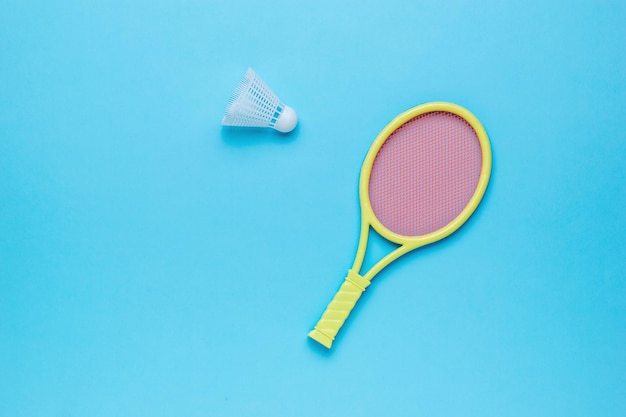 Peteca de badminton e raquete amarela em um fundo azul Conceito esportivo mínimo