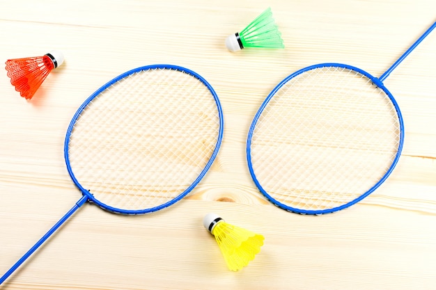 Petecas coloridas e raquetes de badminton planas colocar em cima de madeira