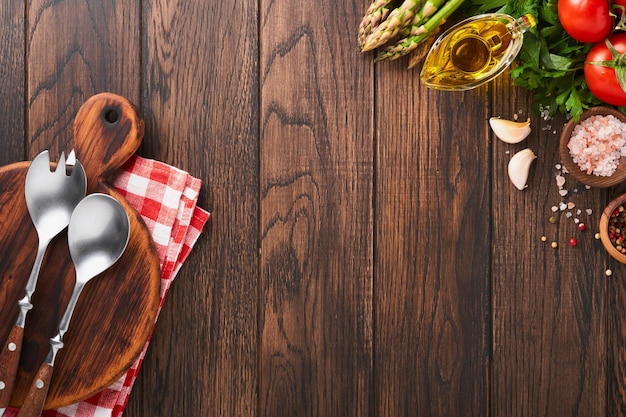 Petersilie petersilie tomate knoblauch olivenöl pfeffer salz holzständer und salatgabel und löffel auf hölzernem kochhintergrund lebensmittelkochhintergrund zutaten zum kochen von lebensmittelhintergrund mock-up