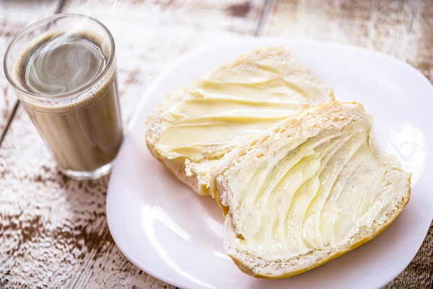 Petisco brasileiro, pão com manteiga chamado cacetinho ou pão francês, servido com café com leite chamado pingado