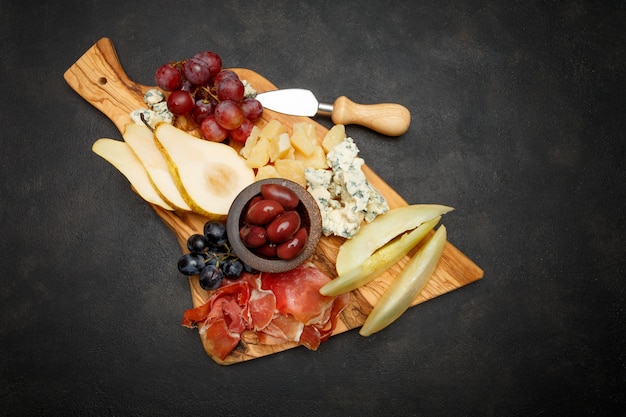 Petisco de antepastos de prato de carne - presunto presunto, queijo azul, melão, uvas, azeitonas