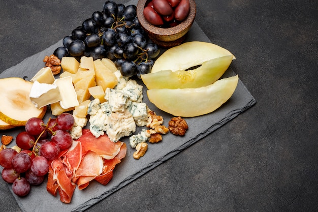 Foto petisco de antepastos de prato de carne - presunto presunto, queijo azul, melão, uvas, azeitonas