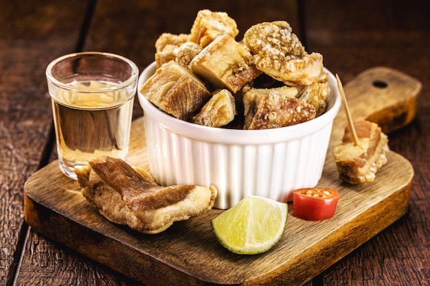 Foto petisco de carne de barriga de porco torresmo crocante típico de minas gerais servido com comida de bar de cachaça brasileira