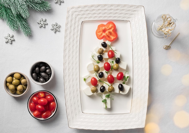 Petiscos em forma de árvore de Natal com queijo, tomate e azeitonas Cenário de mesa festiva