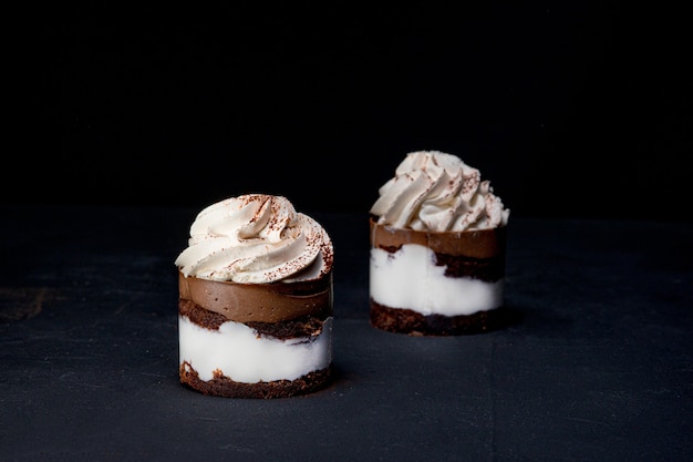 Petit fours o mini tartas de crepe de chocolate con chocolate sobre fondo negro.