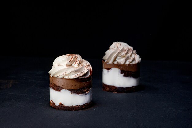 Petit Fours oder Mini-Schokoladen-Crêpe-Kuchen mit Schokolade auf schwarzem Hintergrund.