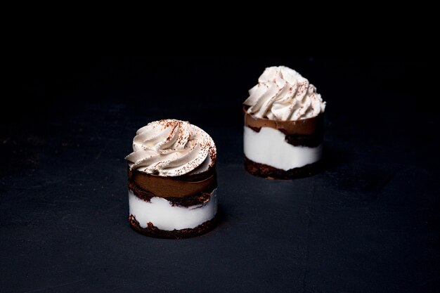 Petit Fours oder Mini-Schokoladen-Crêpe-Kuchen mit Schokolade auf schwarzem Hintergrund.