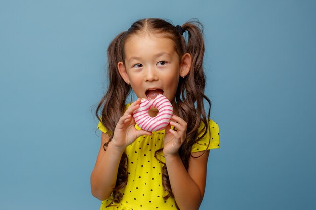 Foto petite, menina asiática, donut, comer, studio, azul, sorriso