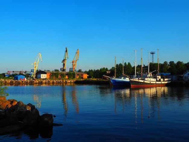 Petrosawodsk Russland 10. Juli 2021 Hafen mit Frachtkränen und Schiffen Vergnügen Holzyachten und Boote Industriegebäude Lake Onega Karelien Seeverkehr und touristisches Thema Der Abend