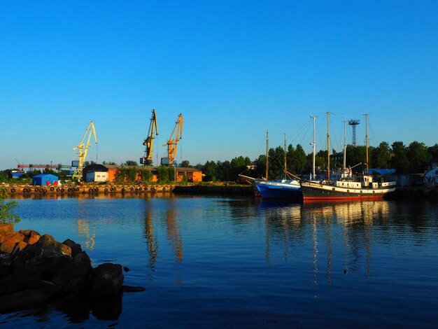 Petrozavodsk Rusia 10 de julio de 2021 Puerto con grúas de carga y barcos Placer yates y barcos de madera Edificios industriales Lago Onega Karelia Transporte marítimo y tema turístico La noche