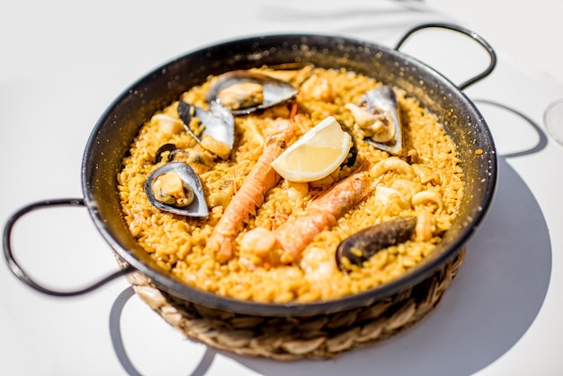 Pfanne mit Meerpaella, valencianisches Reisgericht, auf dem weißen Tisch im Freien