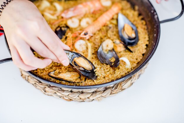 Pfanne mit Meerpaella, valencianisches Reisgericht, auf dem weißen Tisch im Freien