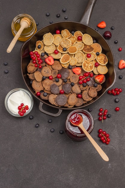 Pfanne mit Müsli-Pfannkuchen. Mehl, Beerenjoghurt, Butter, Honigmarmelade. Gesunder Diät-Snack. Flach liegen. Speicherplatz kopieren