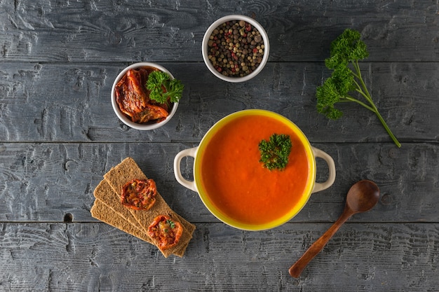 Pfanne mit Pfeffercremesuppe und Zutaten auf einem Holztisch. Suppe der vegetarischen Ernährung