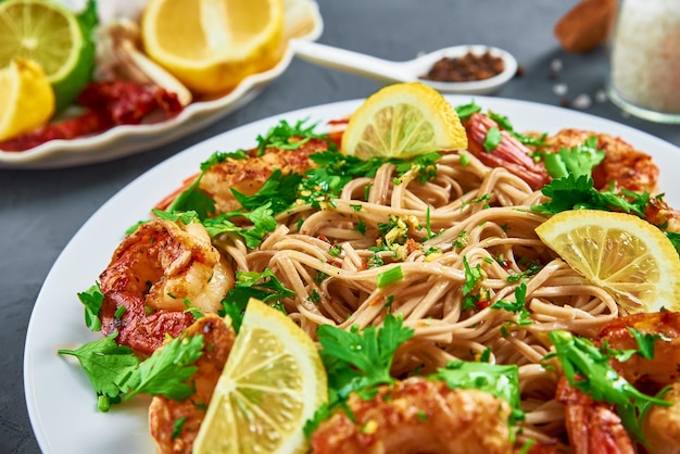 Pfannennudeln mit Garnelen, Zitrone und frischer Petersilie auf weißem Teller, Soba mit Garnelen, asiatische Küche, Draufsicht