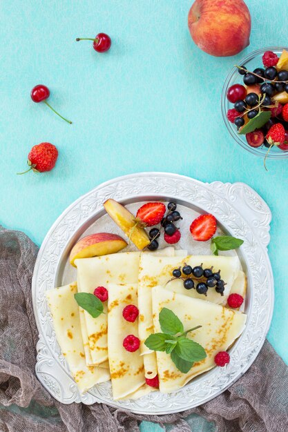 Pfannkuchen auf einem Teller mit Honig und frischen Beeren