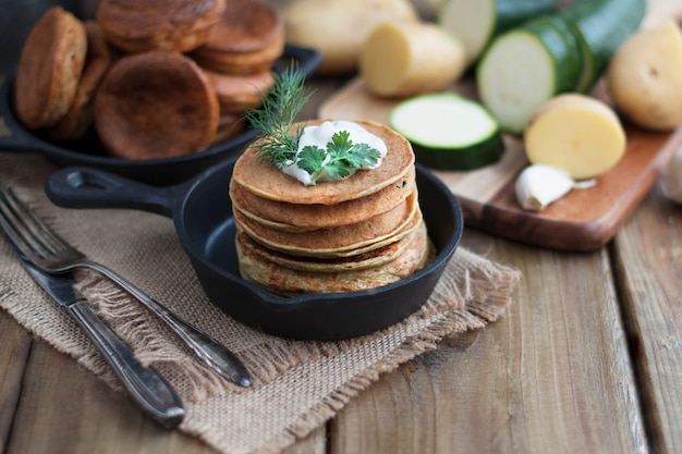 Pfannkuchen aus Gemüse in einer gusseisernen Pfanne auf einem hölzernen Hintergrund