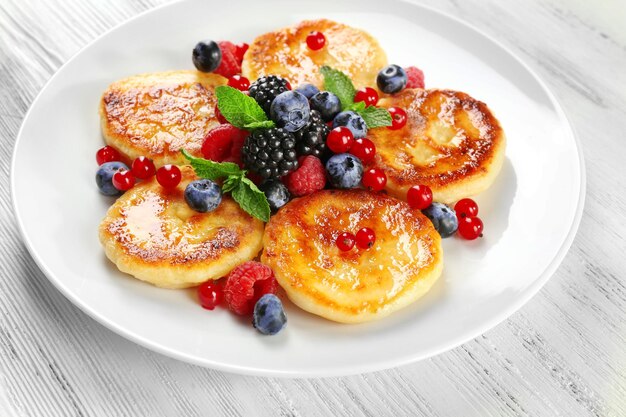 Pfannkuchen aus Hüttenkäse mit Beeren in der Platte auf Holztisch in der Nähe