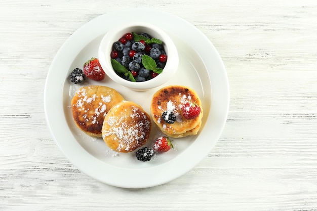 Pfannkuchen aus Hüttenkäse mit Beeren in der Platte auf Holztisch in der Nähe