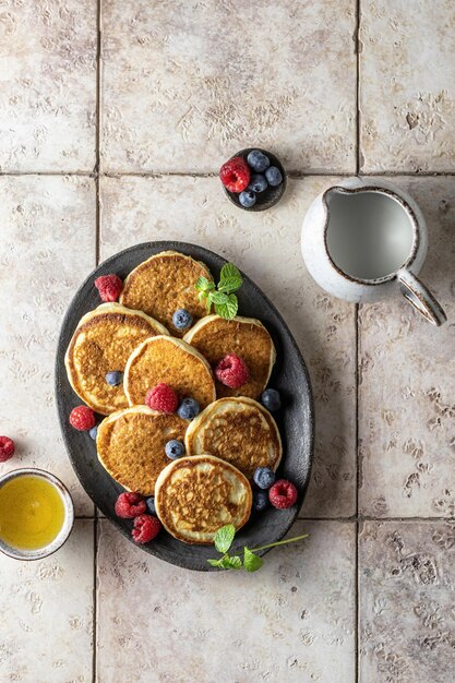 Pfannkuchen in der keramischen Platte mit Himbeerblaubeerminzblatthonig auf einer Draufsicht des rosa Fliesenhintergrundes Beschneidungspfad eingeschlossen