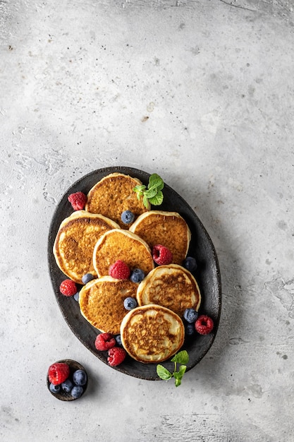 Pfannkuchen in Keramikplatte mit Beerenminzblättern und Sauciere von oben