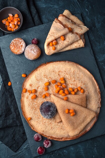 Pfannkuchen m gefrorene Beeren auf einem dunklen Hintergrund.