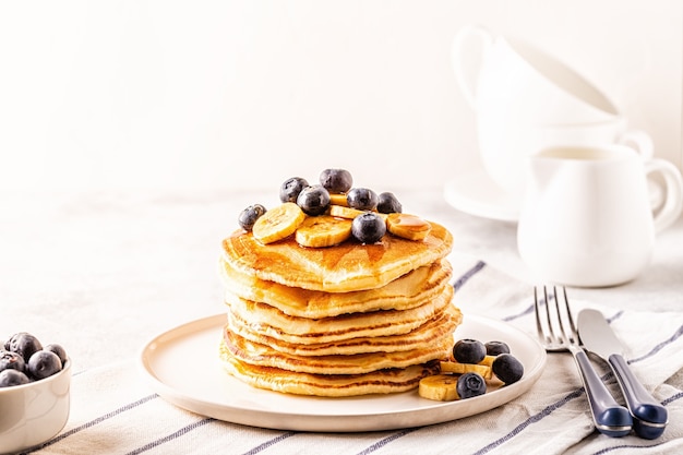 Pfannkuchen mit Banane, Blaubeeren auf weißem Teller, selektiver Fokus.