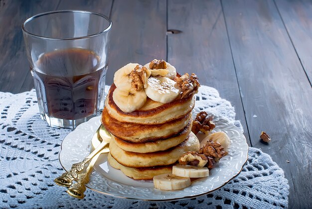 Pfannkuchen mit Banane, Nüssen, Honig und Tasse Kaffee