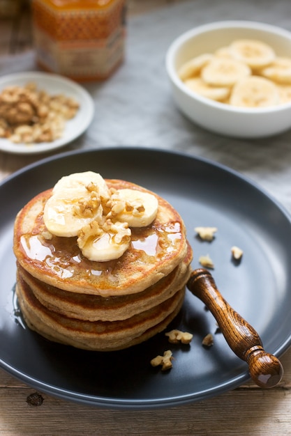 Foto pfannkuchen mit banane, nüssen und honig, dazu tee. rustikaler stil.