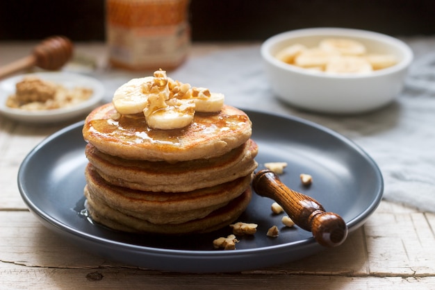 Pfannkuchen mit Banane, Nüssen und Honig, dazu Tee. Rustikaler Stil.