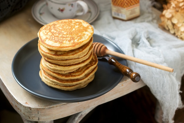 Pfannkuchen mit Banane, Nüssen und Honig, serviert mit Tee. Rustikaler Stil.