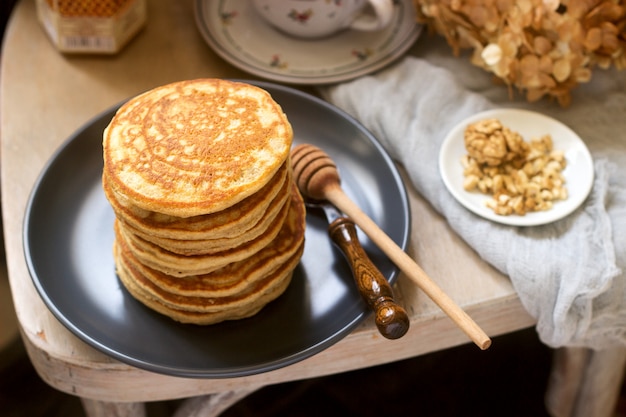 Pfannkuchen mit Banane, Nüssen und Honig, serviert mit Tee. Rustikaler Stil.