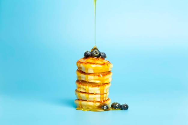 Pfannkuchen mit Beeren auf blauem Bannerhintergrund üppige leckere Pfannkuchen mit Blaubeeren und Sirup...