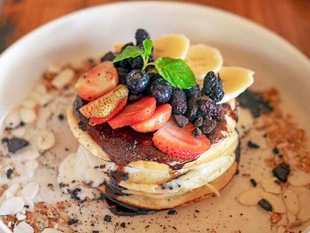 Foto pfannkuchen mit beeren und früchten auf einem weißen teller