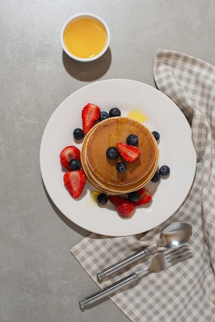 Pfannkuchen mit Beeren und Honig auf einem grauen Tisch